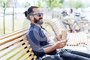 Man with earphones and smartphone drinking coffee