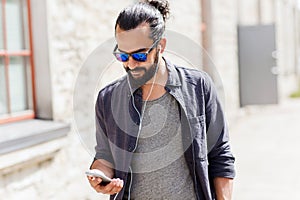 Man with earphones and smartphone walking in city