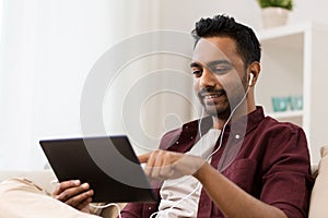 Man in earphones with tablet pc listening to music photo