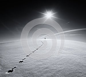 Man.Earth.Universe.Lonely man walking on snow crust field on the trail of a hare on the background of the sun and the flying plane
