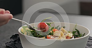 Man eat salad with cherry tomatoes, mixed grens and cheese from white bowl