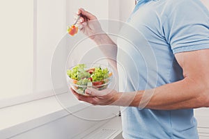 Unrecognizable man has healthy lunch, eating diet vegetable salad