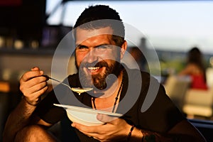 Man eat soup. Good Appetite. Bearded man with bowl of soup. Happy guy eating soup outdoor. Man eating delicious soup in