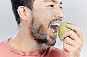 Man is eating apple, health and nutrition with fruit, diet with healthy food and wellness on studio background. Closeup