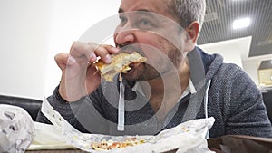 Man eating big hamburger in fast food cafe