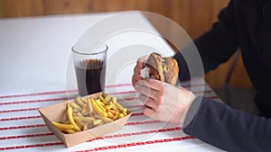 Man eating burger in restaurant enjoying delicious juicy hamburger and french fries