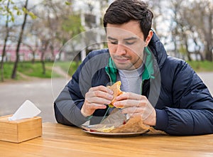 Man eating a burger in street food cafe