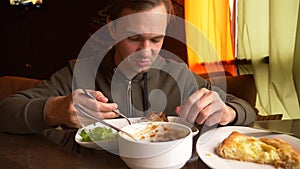 Man is eating in a cafe vegetable salad on a white plate.