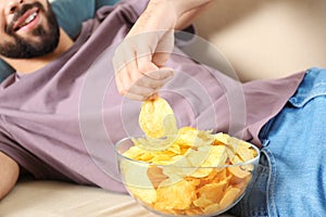 Man eating chips while watching TV on sofa