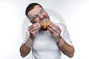 Man eating croissan. He is biting it hard. He likes this french dessert. Isolated on white background.