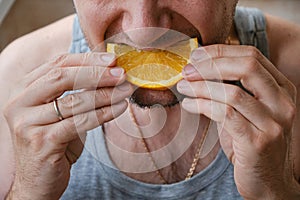 Man eating a fresh orange at home