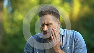 Man eating green apple suddenly feeling sharp dental pain, sensitive teeth