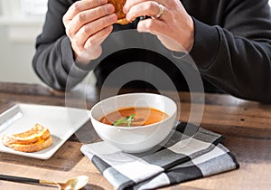 Man eating a grilled cheese sandwich with soup