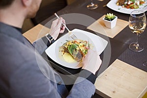 Man eating grilled salmon at restaurant