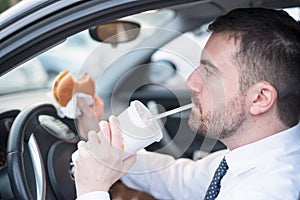 Man eating an hamburger and driving seated in car