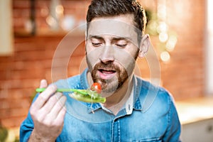 Man eating healthy salad on the kitchhen at home