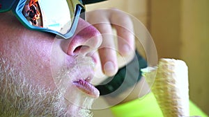 Man eating ice cream. Close-up portrait of young hipster man in sunglases eating ice cream in summer hot weather on the