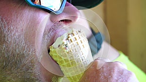 Man eating ice cream. Close-up portrait of young hipster man in sunglases eating ice cream in summer hot weather on the