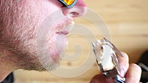 Man eating ice cream. Outdoor closeup portrait of young hipster man in sunglases eating ice cream in summer hot weather