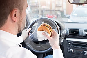 Man eating junk food and driving seated in car