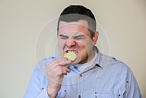 Man eating lemon. Wince from sour taste