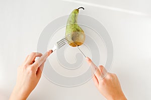 Man eating pear with fork and knife top view. healthy food concept. Healthy products, fruits on a white background. vegetarianism