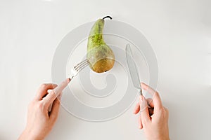 Man eating pear with fork and knife top view. healthy food concept. Healthy products, fruits on a white background. vegetarianism