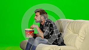 Man eating popcorn and watching a movie. Green screen