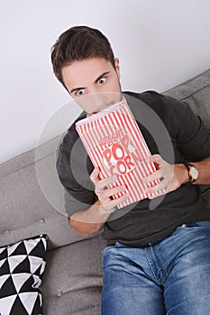 Man eating popcorn and watching movies.