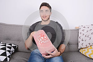 Man eating popcorn and watching movies.