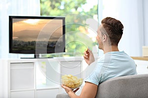 Man eating potato chips while watching TV