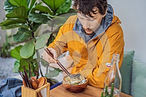 Man eating Raw Organic Poke Bowl with Rice and Veggies close-up on the table. Top view from above horizontal