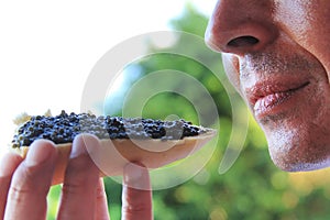 Man eating a sandwich with black caviar