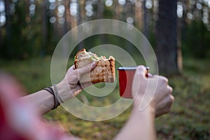 Man eating sandwich drinking tea having break halt in forest enjoying nature, hands close-up.