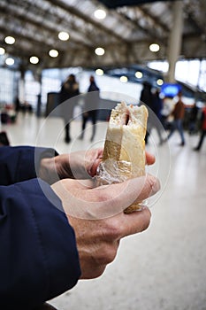 Man eating a sandwich in a train or tram station