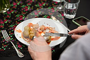 man eating traditional spanish tapas served on plates on black table background. Patatas Bravas with Gambas Ajillo