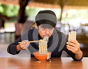 Man eating whilst looking and using smartphone