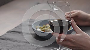man eatings fettuccine with pesto, tomatoes and mozzarella with glass of red wine photo