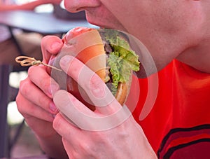 A man eats a big juicy burger. Burger with cheese, vegetables, cutlets close-up