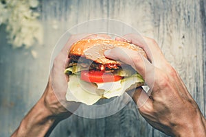 Man eats a big sandwich with meat and wegetables