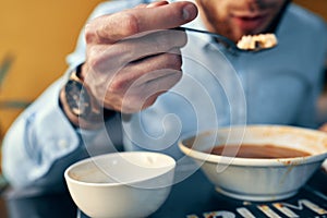 a man eats borscht with sour cream in a restaurant at a table in a cafe and a watch on his hand