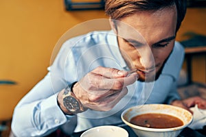 a man eats borscht with sour cream in a restaurant at a table in a cafe and a watch on his hand