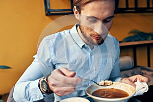 a man eats borscht with sour cream in a restaurant at a table in a cafe and a watch on his hand