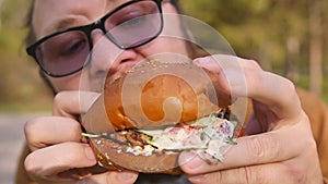 Man eats eating hamburger outdoors. Close-up