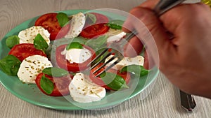 A man eats the Italian caprese salad.juicy fresh tomatoes, creamy mozzarella, fresh basil, and extra virgin olive oil.Healthy food