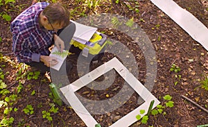 The man ecologist describes the plants inside the square marking site.