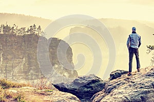 Man on edge of cliff high above misty valley. Travel hiking and Lifestyle.