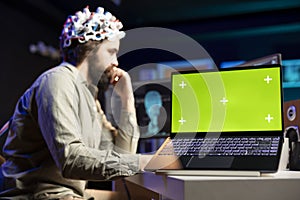 Man with EEG headset transferring mind into virtual world, chroma key laptop photo