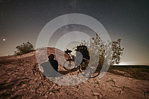 Man with electric bike looking on night starry sky in moon light