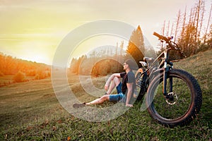 Man with an electric fatbike on the background of the sunset. Picturesque place in the village. Concept of a healthy lifestyle